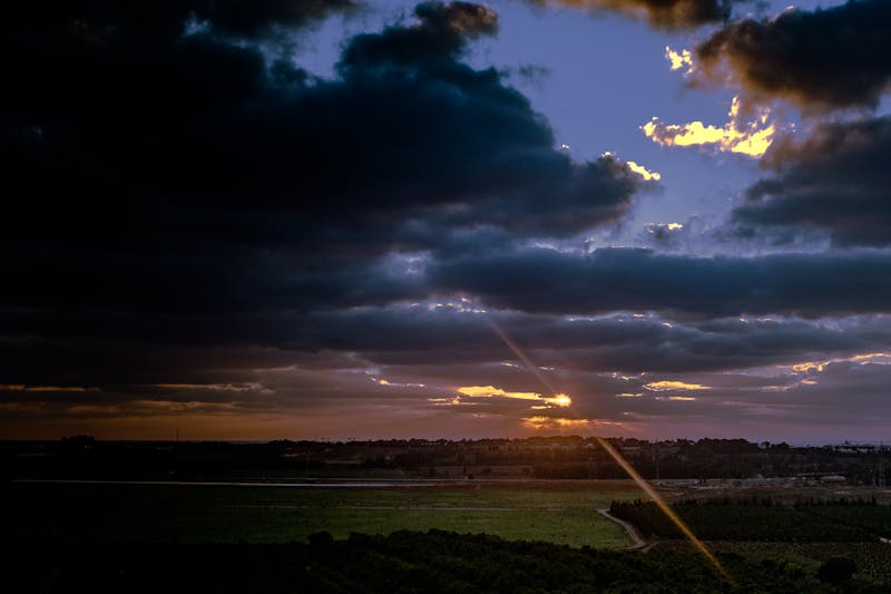 Sunrise light breaking through clouds over open countryside fields